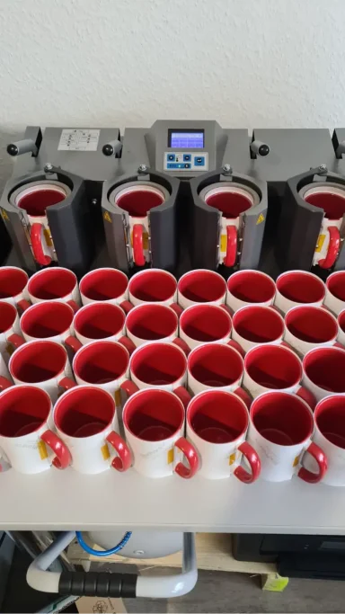 Eine Anordnung von Kaffeetassen mit rotem Inneren auf einem Tisch.