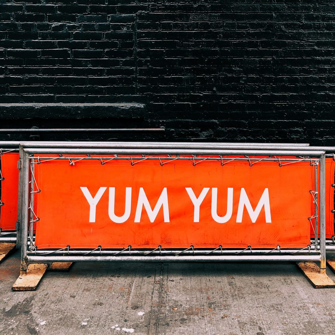 Werbebanner & großformatige Außenwerbung Orange Banner mit dem Text "YUM YUM" in großen weißen Buchstaben.