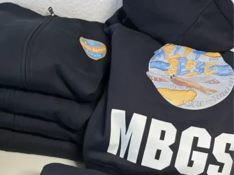 Navy Sweatshirts gestapelt, mit buntem Logo und Aufschrift "MBGS".