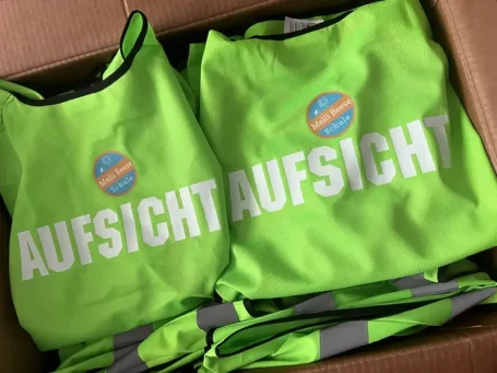 Grüne Warnwesten mit dem Aufdruck "AUFSICHT" in großen Buchstaben.