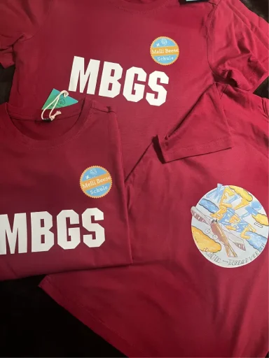 Rote T-Shirts mit dem Aufdruck "MBGS" und einem runden Farblogo.