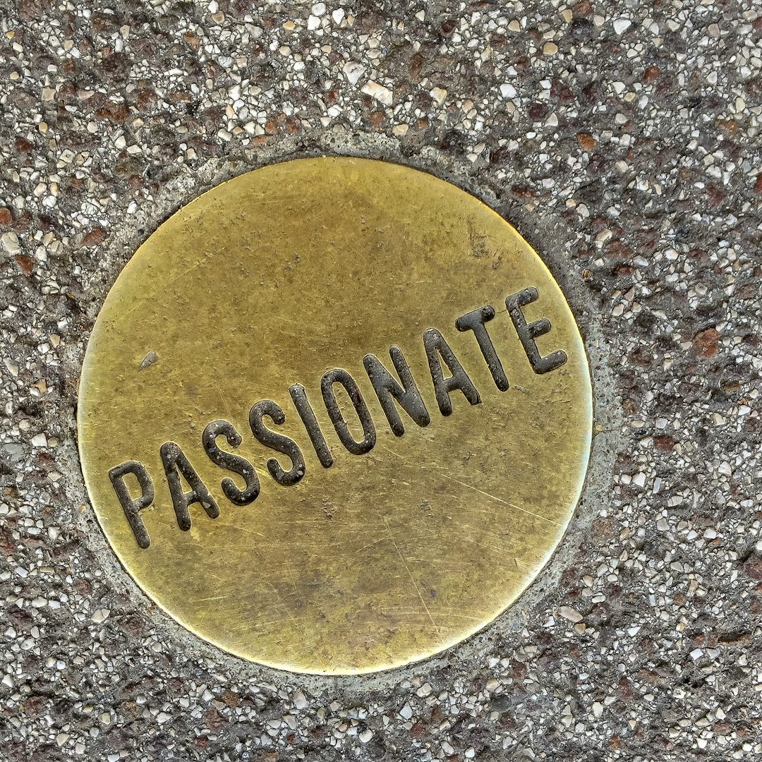 Runder, bronzefarbener Medaillon mit der Prägung „PASSIONATE“ mit der Bedeutung auf deutsch übersetzt = Leidenschaft.