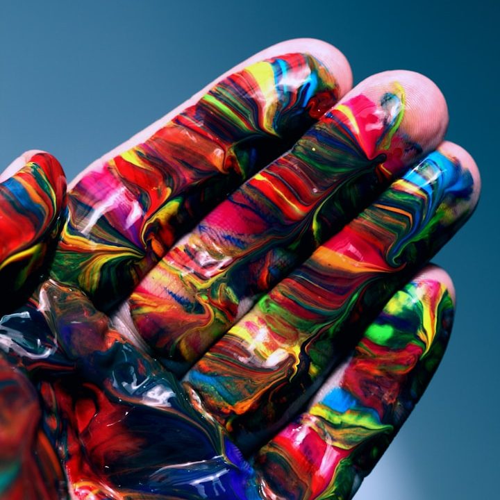 Bunte, marbelierte Farben auf einer Handfläche mit nassen Farbresten. Kreativität und Vielfalt sollen verdeutlicht werden.
