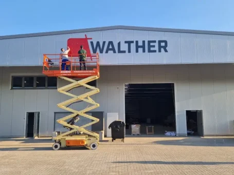 Zwei Arbeiter auf einer Hubarbeitsbühne vor der Walther-Fabrik.