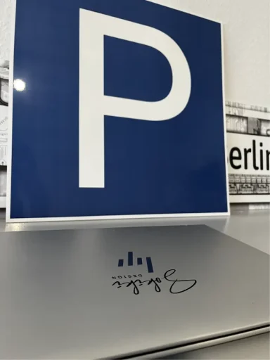 Parkschild Parkplatzschild mit großem "P" vor einem Laptop mit grafischem Design.