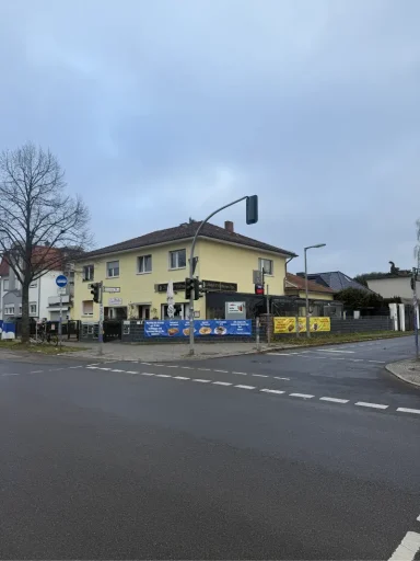 Kneipe mit Bannern Gelbes Haus an einer Straßenecke mit Verkehrsampel und Baustellenschildern.