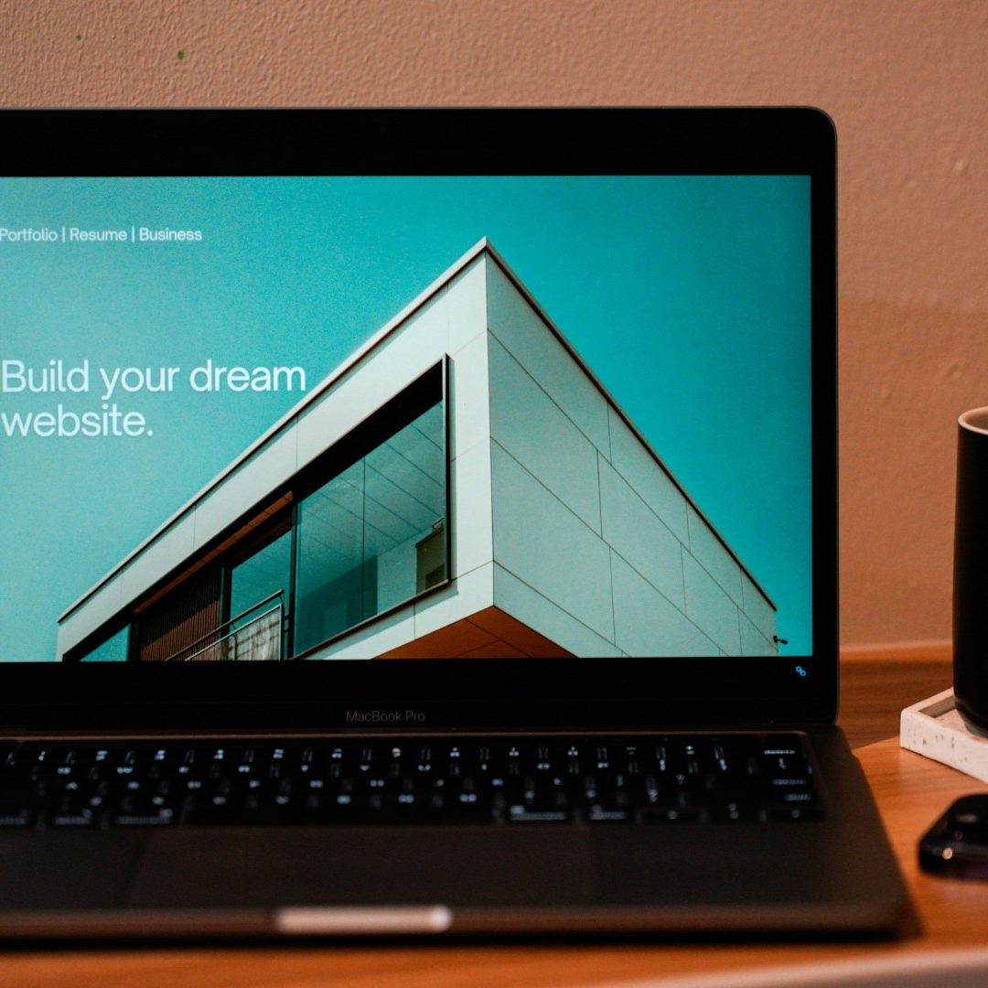 Laptop mit einer Webseite über den Bau von Traumhäusern und einer Kaffeetasse daneben.