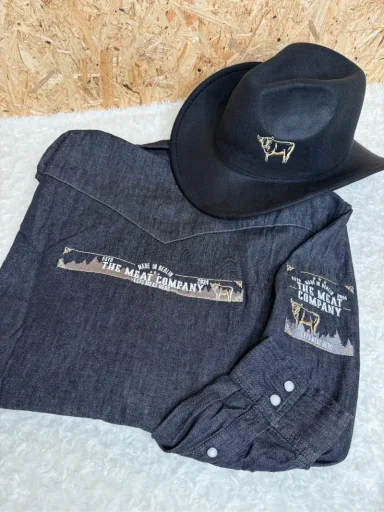 Schwarzes Cowboy-Hut und blaues Hemd mit dekorativem Aufdruck und Knöpfen.