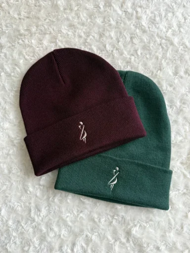 Zwei Mützen in Dunkelrot und Dunkelgrün mit einem kleinen Logo.