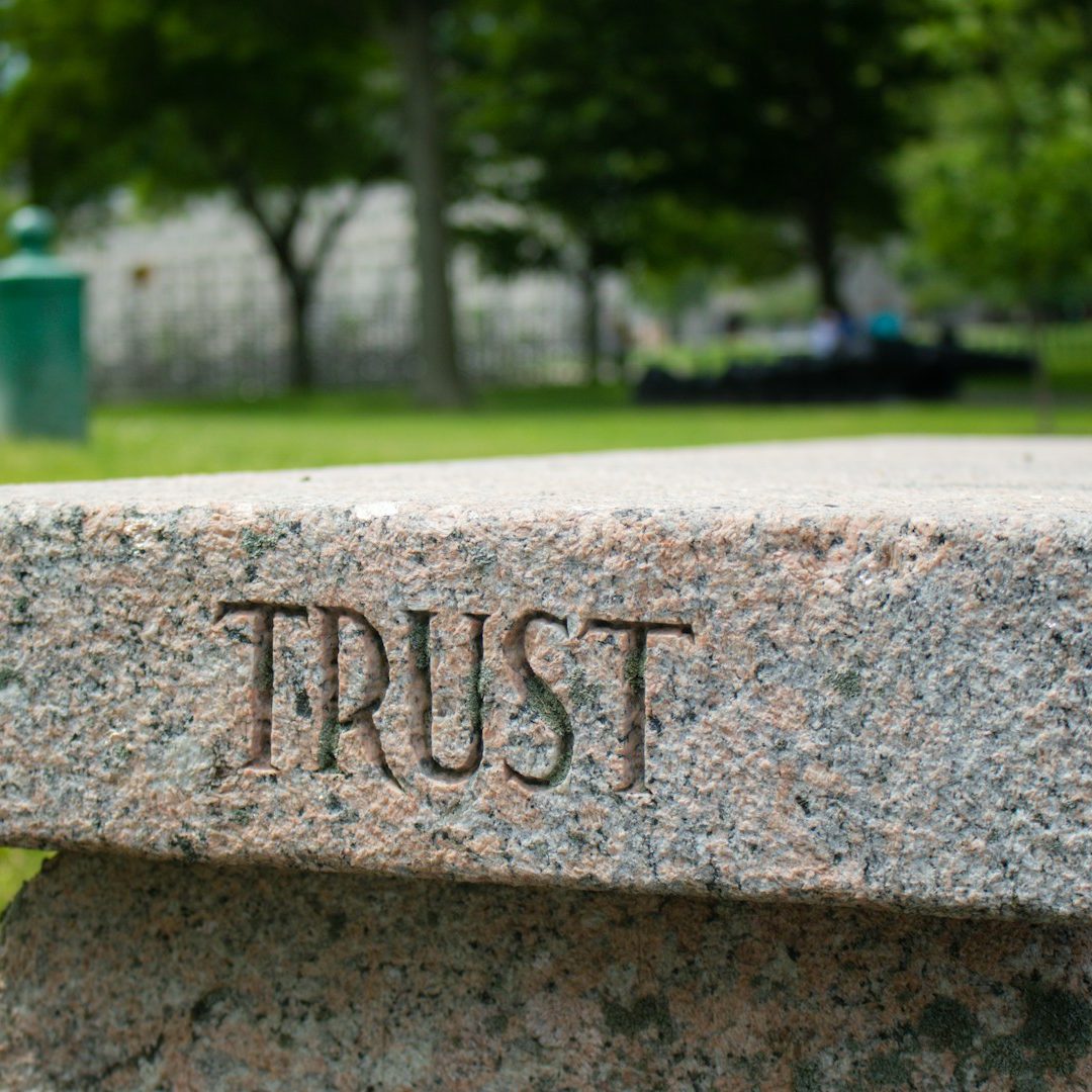 Granitplatte mit der eingravierten Aufschrift "TRUST" im Freien.