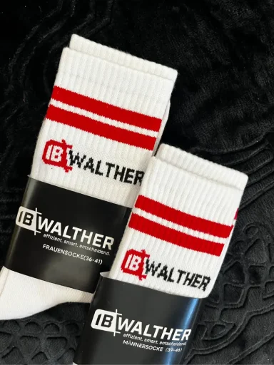 Weiße Socken mit roten Streifen und WALTER-Logo auf schwarzem Hintergrund.