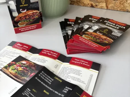Menü mit verschiedenen Gerichten und Getränken, umgeben von mehreren Flyern.