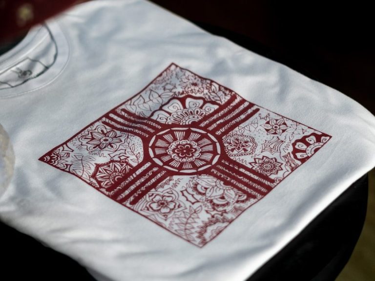 Weißes T-Shirt mit rotem, kreisförmigem Grafikdesign und floralen Mustern.