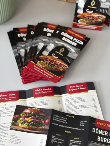 Mehrere Speisekarten von einem Dönershop liegen auf einem Tisch.