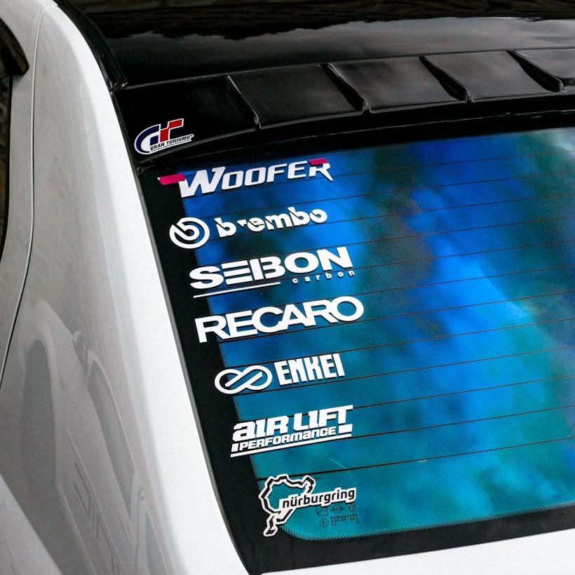 Fahrzeugfolierung & mobile Werbung Aufkleber verschiedener Marken auf der Heckscheibe eines Autos.