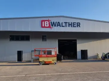 Fassade eines Lagerhauses mit dem Schriftzug "IB WALTHERS" und einem Arbeitsbock davor.