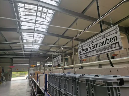 Druck auf Schild Blick in ein Gebäude mit Regalen und einem Schild über Schrauben unter einem Glasdach.