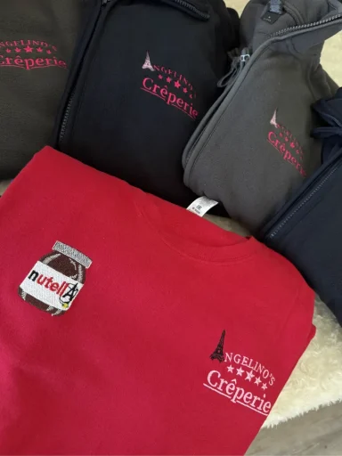 Verschiedene Kleidungstücke in Schwarz, Grau und Rot mit dem Logo einer Marke.