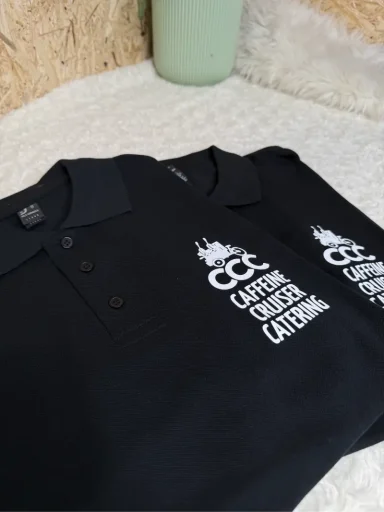 Schwarze Poloshirts mit Logo von Catering Services auf einem hellen Hintergrund.