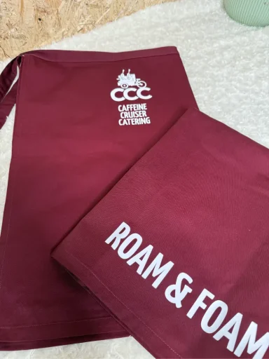 Zwei burgunderrote Stoffbeutel mit den Aufschriften "CCC" und "ROAM & FOAM".