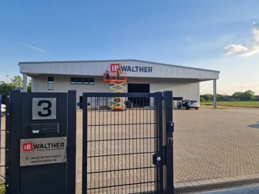 Logoschild Moderne Lagerhalle mit Firmenlogo und Parkplatz in ländlicher Umgebung.